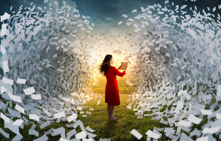 A woman holding a book is surrounded by giant waves of pages.の写真素材