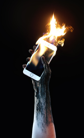 Hand holding a burning cell phoneの写真素材