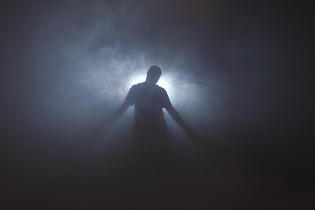 A man stands in front of a bright light with fogの写真素材