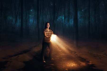 A woman uses a Bible to light her pathの写真素材