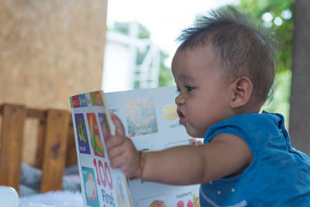 Close up of little baby while the baby learning to reading from mother or looking at the book on the mother's hands (education baby or baby growing up concept) (soft focus)の写真素材
