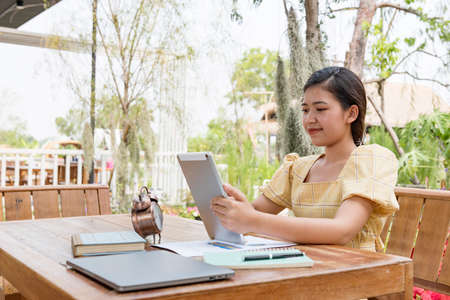 A side view of a smiling Asian woman freelance who works happily at home.