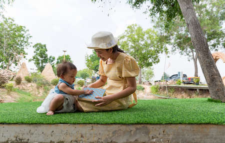 Cute girl reading a book with his mother, Asian mother and child, concept Strengthen the development of children's love for reading.の写真素材