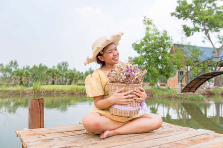 Happiness, a beautiful woman in the garden, placed in a hat, holding flowers.の写真素材