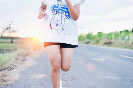 Asian female runner, she runs on the road in the evening sunset.の写真素材