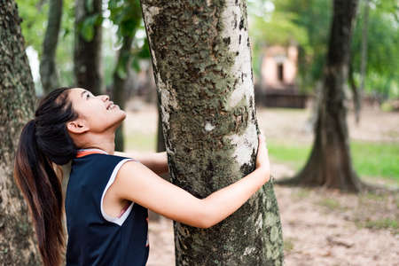 girl hugging a big tree Love nature, smile happily.の写真素材