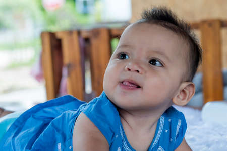 A beautiful 6 month old baby with big eyes lies on the bed.の写真素材