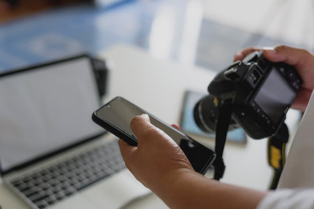 The hands of men use smartphones with DSLR cameras in the studio and the sun light.の写真素材