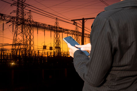 Electrical engineer with high voltage pylon at sunrise background,High voltage power plant at sunset, high voltage transmission tower.の写真素材
