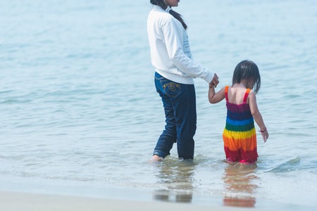 Asian mother and daughter playing together on the beach at the sea.の写真素材