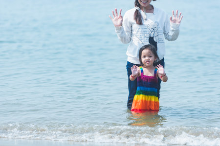 Asian mother and daughter playing on the beach in the summer time.の写真素材