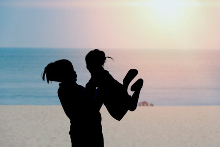 Silhouette. Mother and daughter playing on the beach at sunset.の写真素材