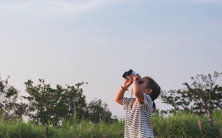 Cute girl looking through binoculars, concept of hiking, camping and adventure.の写真素材