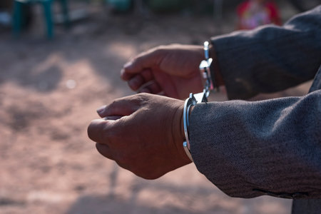 Businessman arrested for corruption. Man in a suit with handcuffs on his hands.の写真素材