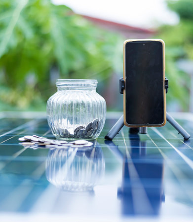 Coin and blurred solar panel cell on background with copy space. Money business in renewable energy power resources concept.の写真素材