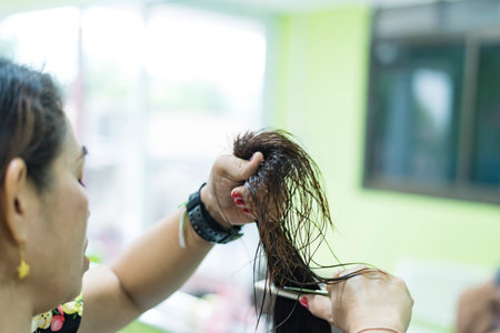 Hairdresser trims black hair with scissors.の写真素材