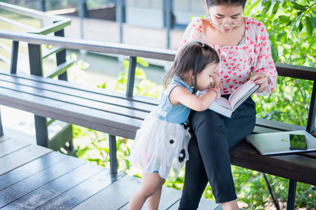Asian mom with laptop working on desk from home along with raising a small child.の写真素材