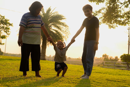 Silhouette, diversity of young women and girls walking in the park with LGBTQ family. Family enjoying outdoor activities behind the garden in the evening.の写真素材