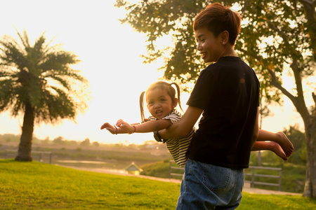 Silhouette, diversity of young women and girls walking in the park with LGBTQ family. Family enjoying outdoor activities behind the garden in the evening.の写真素材