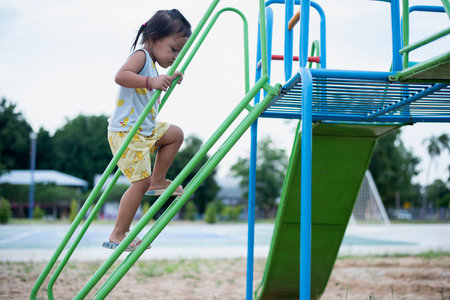 A girl is climbing up a steel ladder to a slide in a playground.