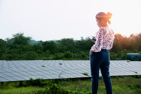 Asian female mechanic inspecting solar panel maintenance Caucasian engineer at solar power station.の写真素材