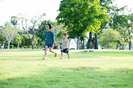 Happy Southeast Asian girls playing outdoors in the spring park. Asian children playing in the garden Summer vacation.の写真素材