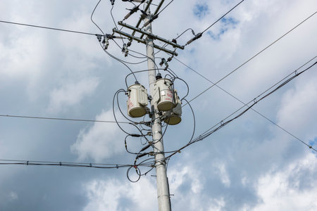 Concrete gray round electric pole with transverse brown metal diamond-shaped frames construction...