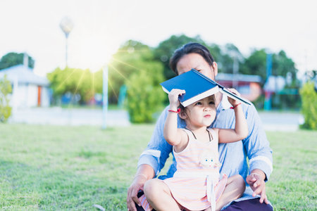 Girl with book on her head outdoors Female student portrait, education concept Happy cute kid smiling with learning.の写真素材