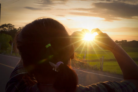 Young woman take a picture of sunset on the road in the countryside.の写真素材