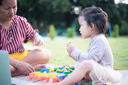 Daughter and mother playing with legos on the front yard. Concept of early learning and development.の写真素材