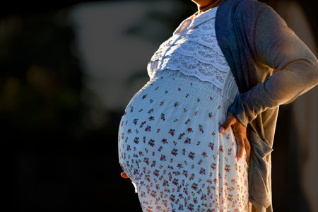 Side view close-up of pregnant woman touching her belly. Pregnancy health & wellbeing concept.の写真素材