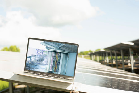 Engineer uses laptop computer to inspect solar panels, solar cell farm Concept of economic energy...
