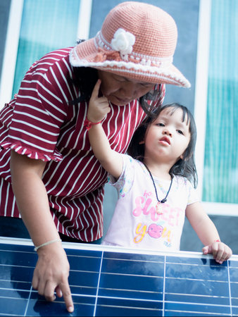 A happy Asian family admires the solar panels they just installed at their home.の写真素材