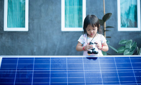 Happy Asian girl admiring solar panels with binoculars recently installed at home.の写真素材