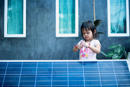 Happy Asian girl admiring solar panels with binoculars recently installed at home.の写真素材