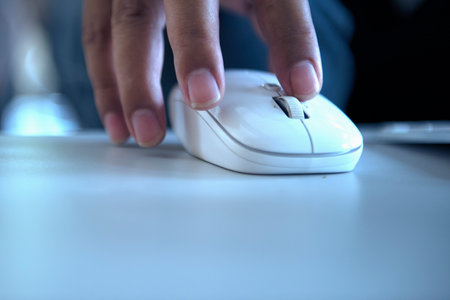 Handling the mouse of a computer on a wooden tableの写真素材
