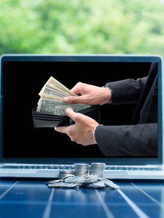 A bag full of money and a pile of coins on a solar panel The idea of installing solar cells gives...