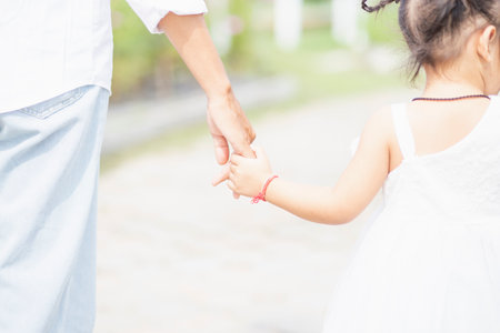 Little girl with her father on nature background A back view of the Father in Heaven concept. Father holds daughter's hand as she walks.の写真素材