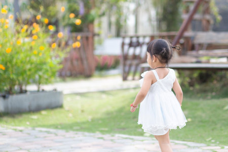 A happy young girl admires and gently touches and admires a blooming flower. It reflects the beauty of spring and the simple pleasures of being in contact with nature. Spring awakening concept and growth.の写真素材