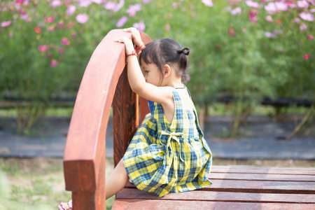 A young girl sits on a wooden bridge happily watching the flowers bloom.の写真素材
