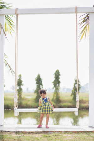 A young woman sits on a swing and admires the breathtaking view of beautiful nature.の写真素材
