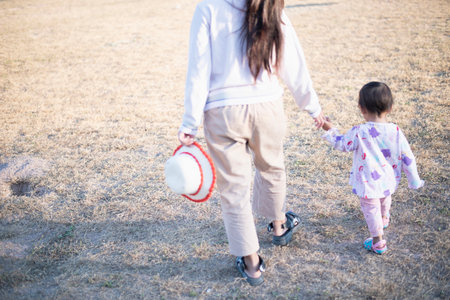 Mother and daughter playing and running around the park on beautiful morning.の写真素材