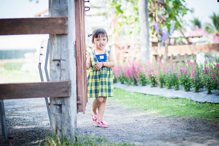A girl opens the door to a flower garden and welcomes herself into beautiful nature.の写真素材