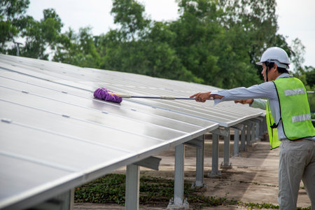 Asian workers clean solar panels after outdoor installation on a solar cell farm.