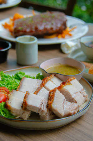 Roast pork with sauce and salad on wooden table.の写真素材