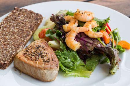 Tuna Steak and vegetable salad with shrimps and breadの写真素材