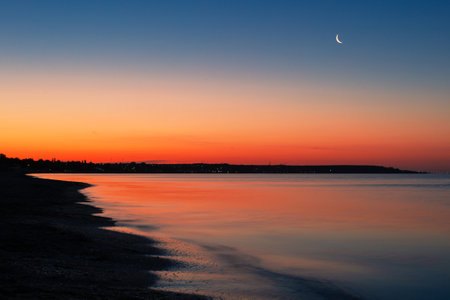 Beautiful sunset over the Sea with the moon in the skyの写真素材