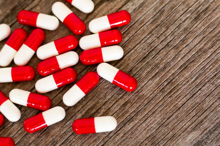 Medicine white-red capsules on wooden background.の写真素材