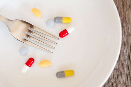 Medicine for healthcare with fork on white dish and wooden background.の写真素材