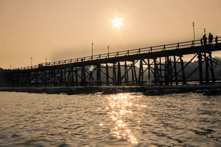 Saphan Mon (Mon Bridge), the large old wooden bridge across Song Karia river to the village, in the evening, located in Sangklaburi District, Kanchanaburi, Thailandの写真素材